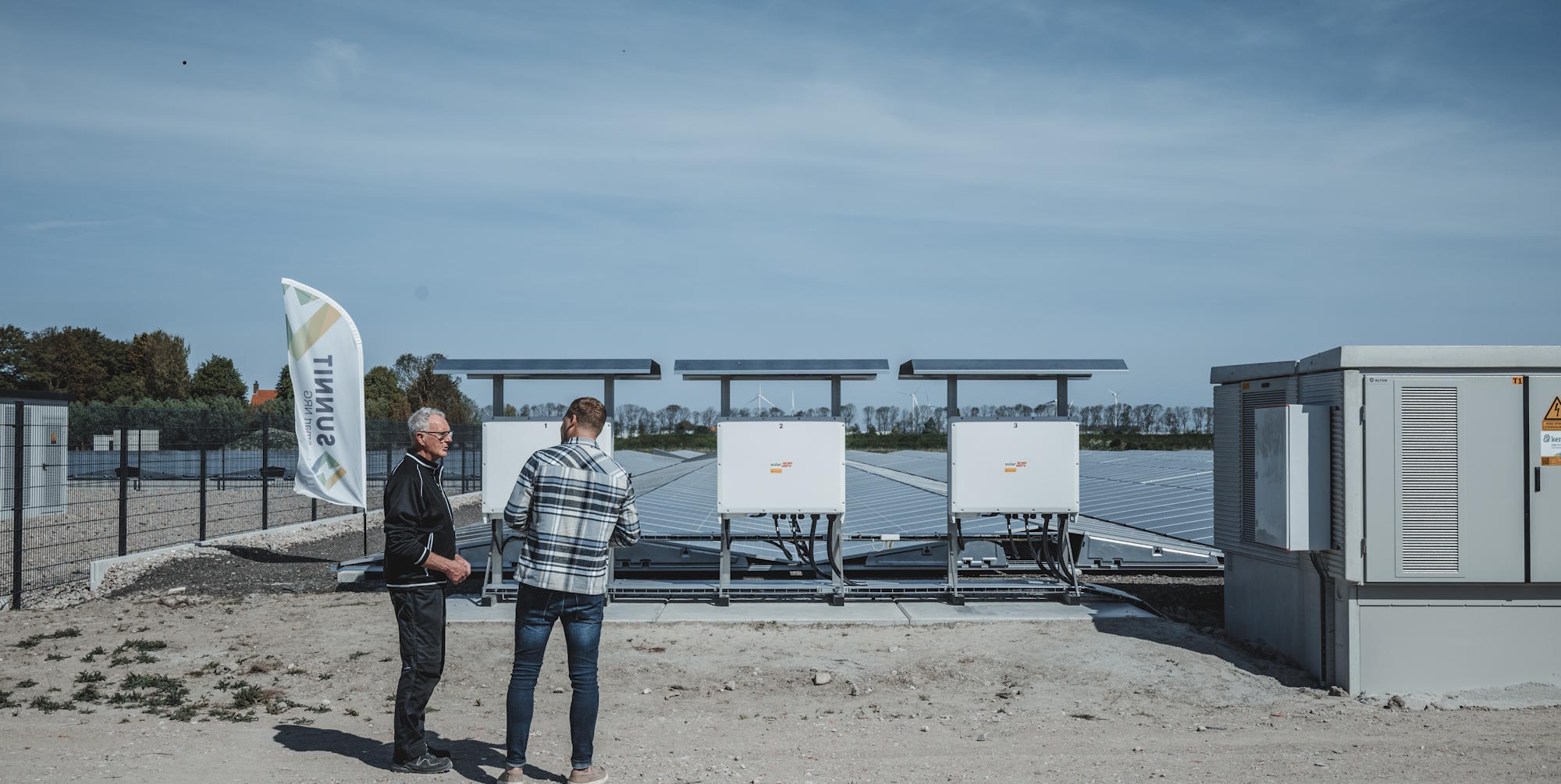 Twee mannen praten bij veld van zonnepanelen